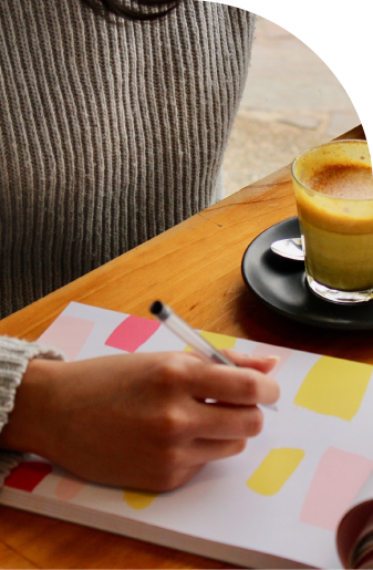 Woman writing in a notebook with a coffee