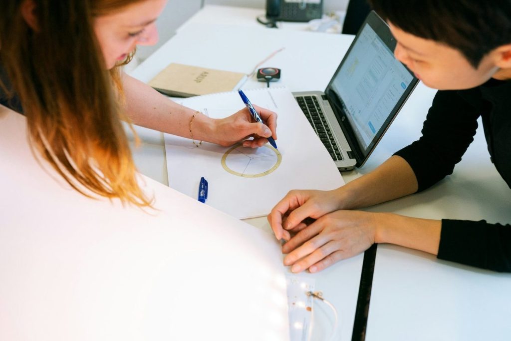 Team members working together drawing with a laptop on the table
